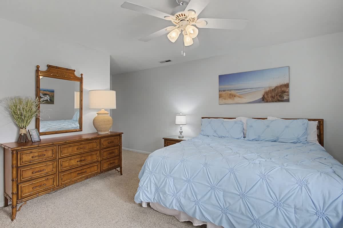 Drift off peacefully in your coastal-themed bedroom with soft blue linens and calming beach artwork creating the perfect seaside sanctuary.