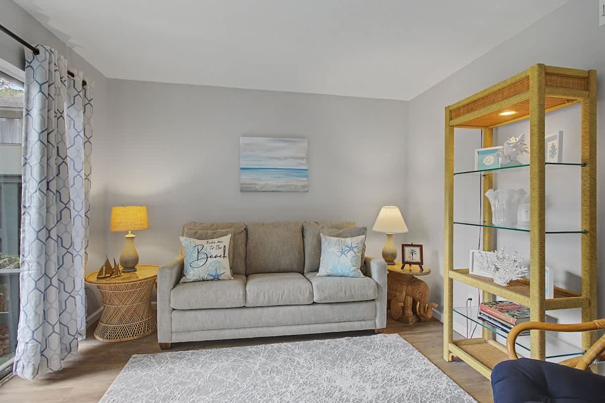 Sink into your cozy sofa surrounded by coastal touches, wicker warmth, and beach-themed art that makes this space your perfect home base.
