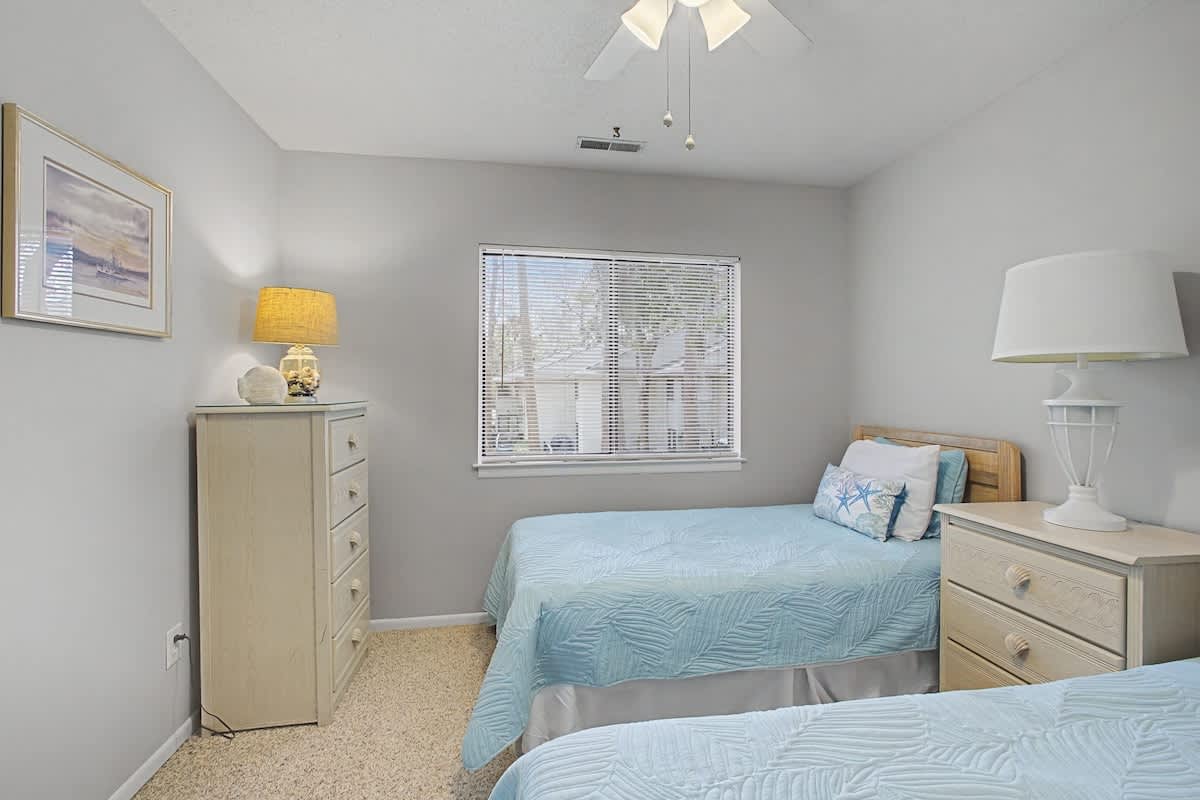 Settle into your peaceful twin bedroom with soft coastal colors and gentle natural light streaming through your window.