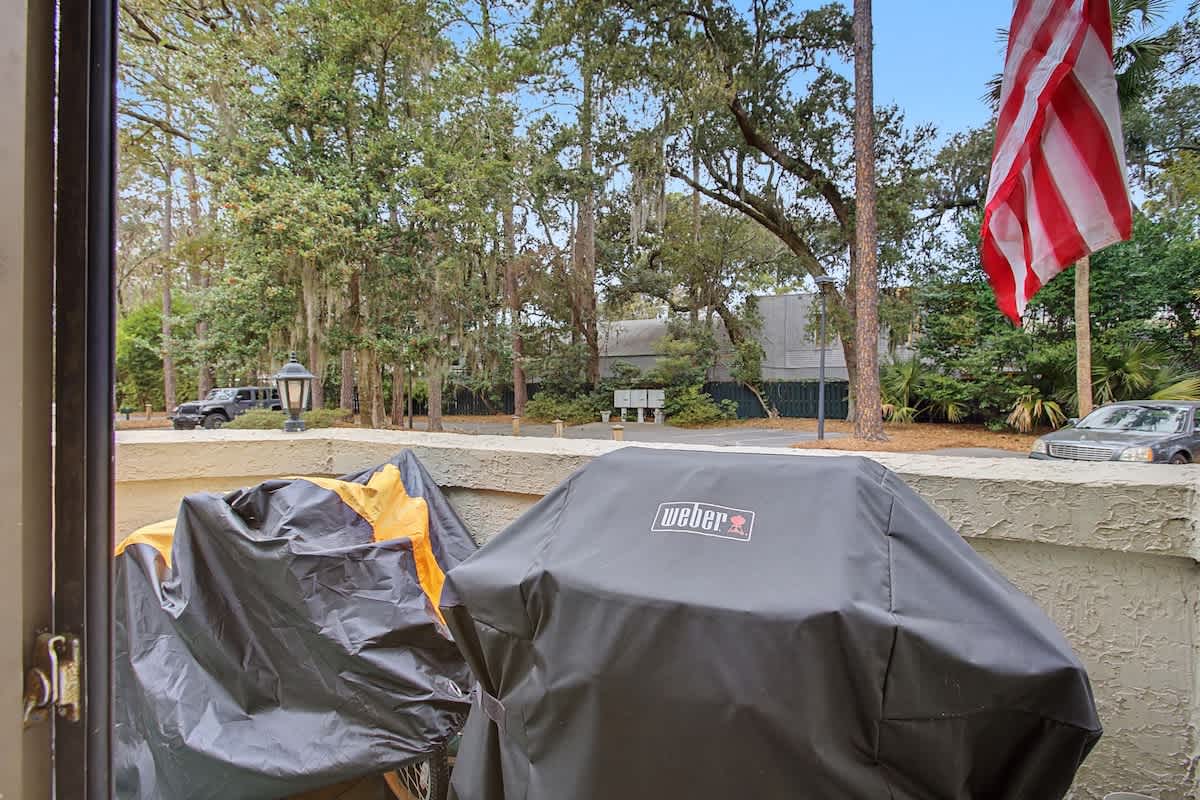 Your covered Weber grill awaits perfect outdoor cooking moments on the patio, while leafy neighborhood views create a peaceful backdrop.