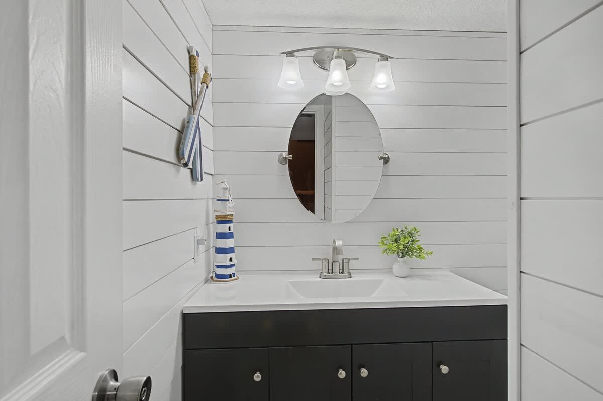 Refresh in your charming coastal bathroom with crisp white shiplap walls, modern vanity, and nautical touches that create a serene seaside retreat.