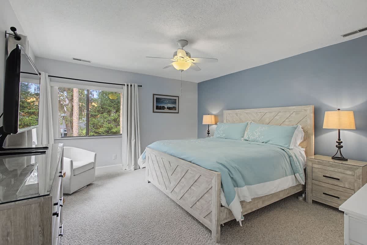 Drift off peacefully in your serene bedroom featuring soothing coastal colors, warm bedside lighting, and garden views.