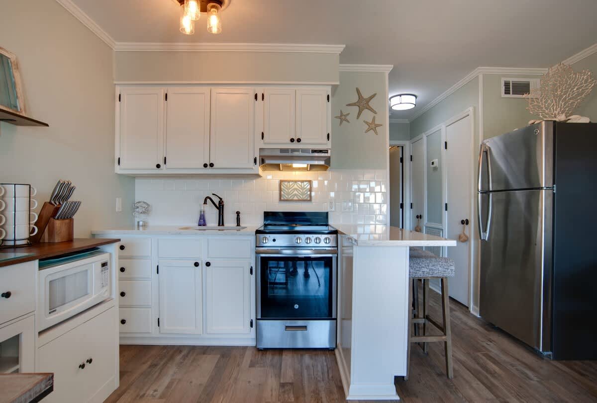 Your coastal-inspired kitchen features crisp white cabinets, subway tile backsplash, and modern stainless appliances, perfect for preparing meals.