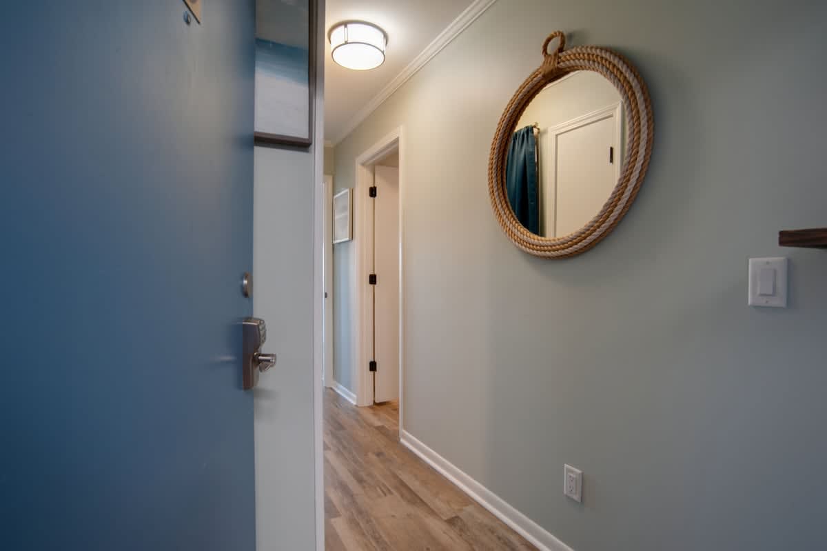 Step into your coastal-inspired entryway, where nautical charm meets modern comfort with rope-wrapped mirrors and soothing blue accents welcoming you home.