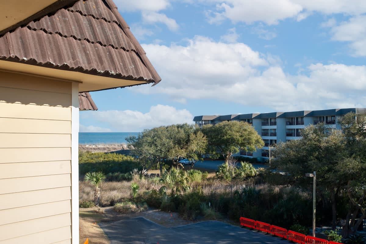 Beachfront property offers stunning ocean views with nearby resort buildings nestled among lush coastal vegetation and tropical landscaping.