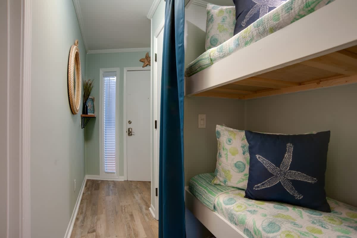 Cozy bunk beds with ocean-themed linens create your perfect coastal retreat, complete with privacy curtains for peaceful sleep.