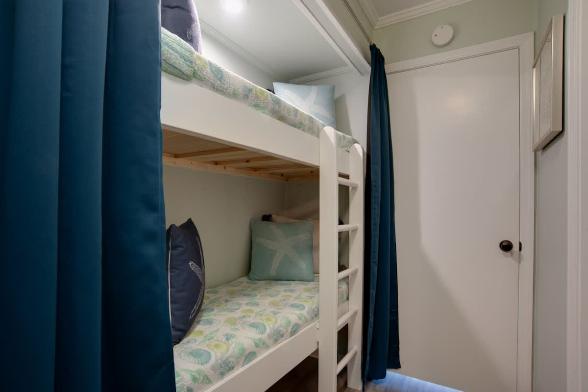 Your cozy bunk room features charming nautical bedding and privacy curtains, perfect for restful nights after beach adventures.