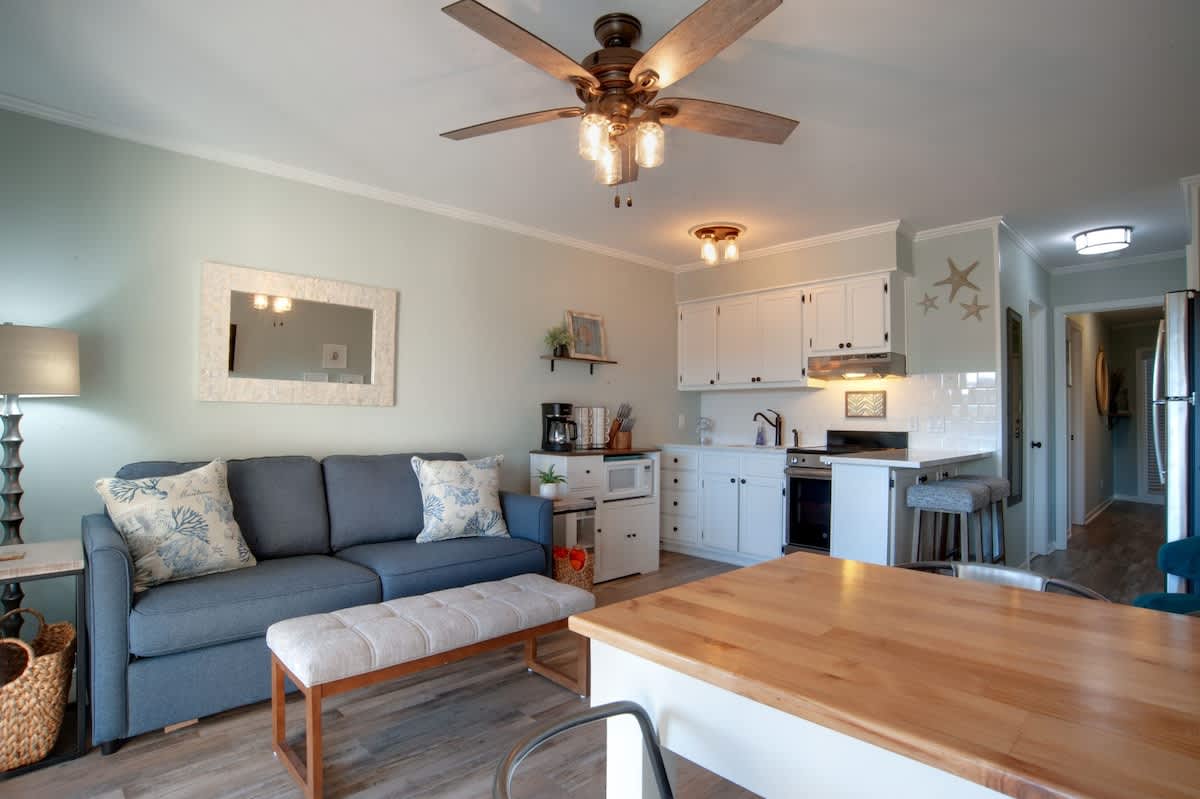 Relax in your bright, coastal-inspired retreat where soft blues and whites create perfect harmony. Your open-plan space flows beautifully from cozy seating to modern kitchen.