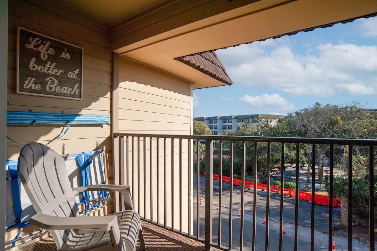 Sip your morning coffee on your private balcony, with comfy chairs and a charming beach sign setting the perfect coastal mood.