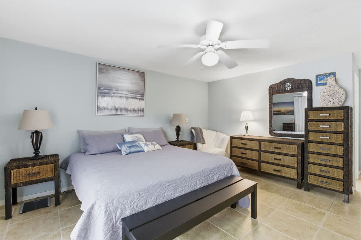 Your peaceful bedroom sanctuary features a comfortable bed, stylish wicker furniture, and coastal artwork to help you unwind completely.