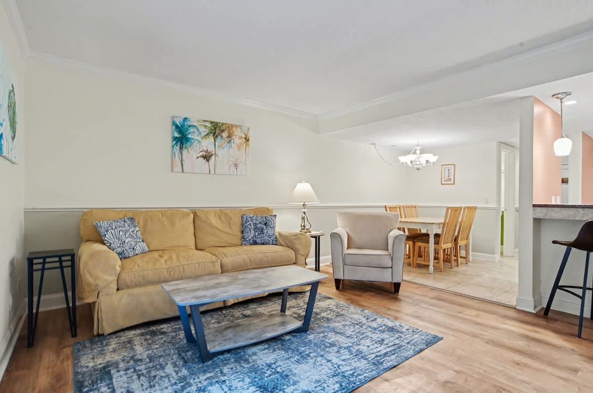 Relax in your bright, welcoming living space featuring comfortable seating, tropical artwork, and an open layout perfect for unwinding after exploring.