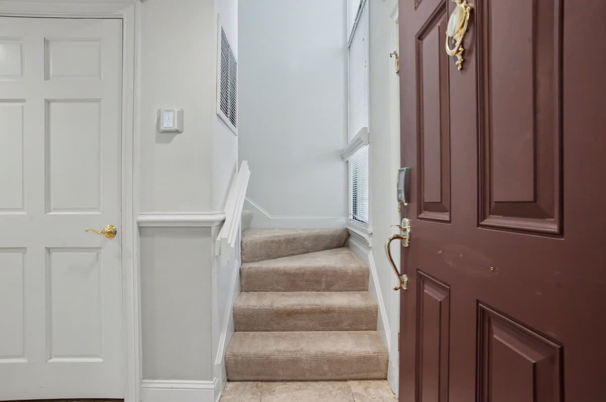 Step into your welcoming entrance where warm wood doors and soft carpeted stairs create an inviting atmosphere for your home away from home.