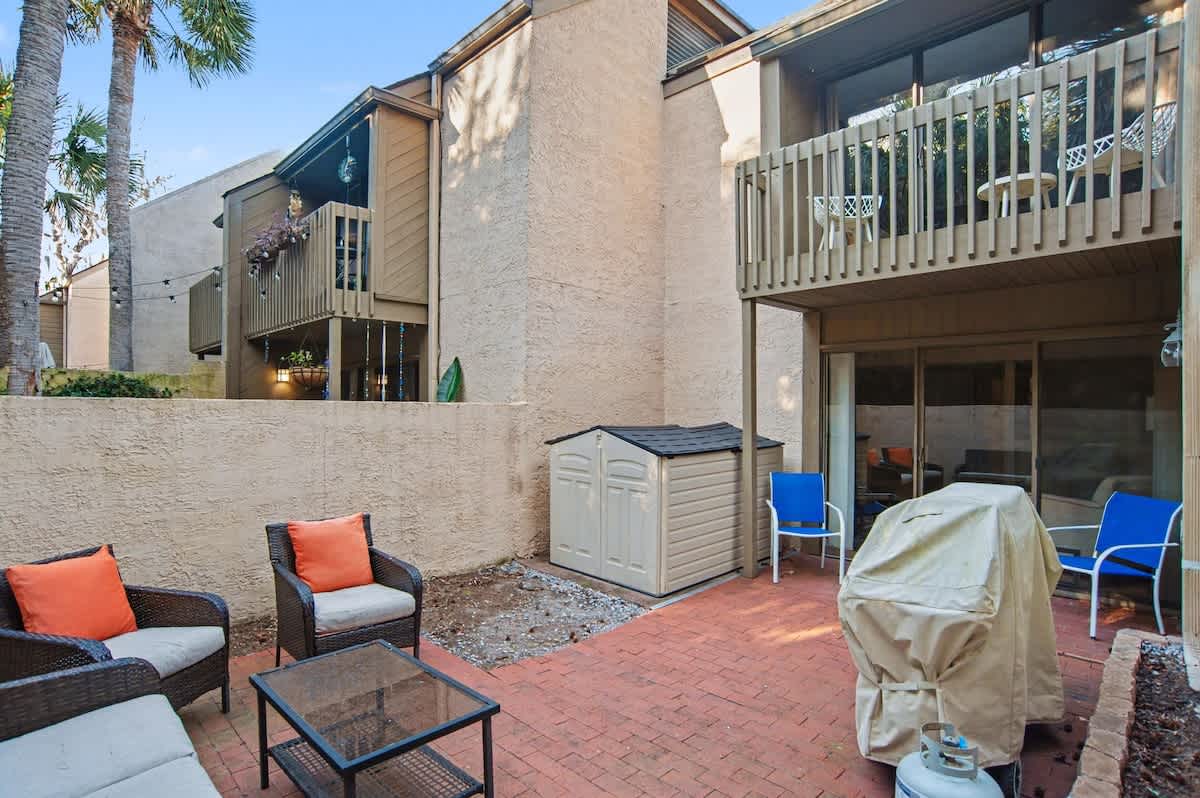 Relax in your private brick patio with comfortable outdoor seating, perfect for morning coffee or evening gatherings under swaying palm trees.
