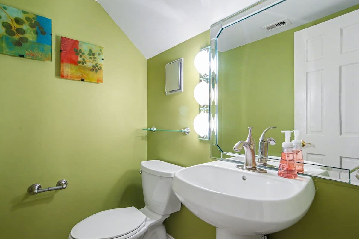 Freshen up in your vibrant bathroom featuring modern fixtures and cheerful green walls that create an energizing start to your day.