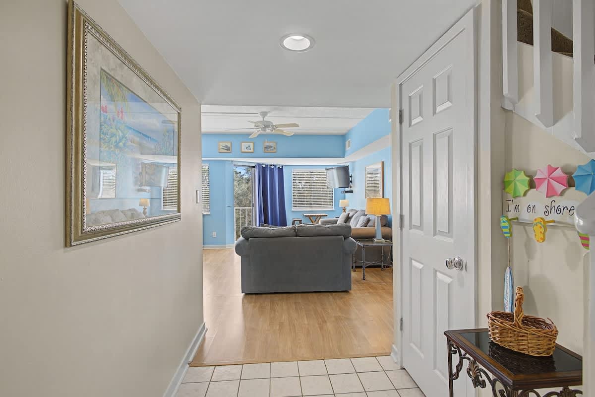 Step into your bright coastal haven where cheerful blue walls and comfortable seating create the perfect space to unwind after beach adventures.