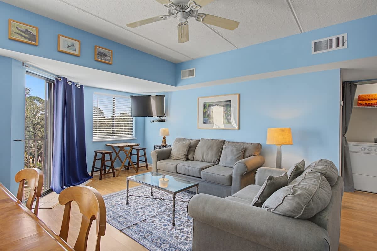 Relax in your bright living space with plush seating, warm lighting, and refreshing blue walls that create a coastal vibe.