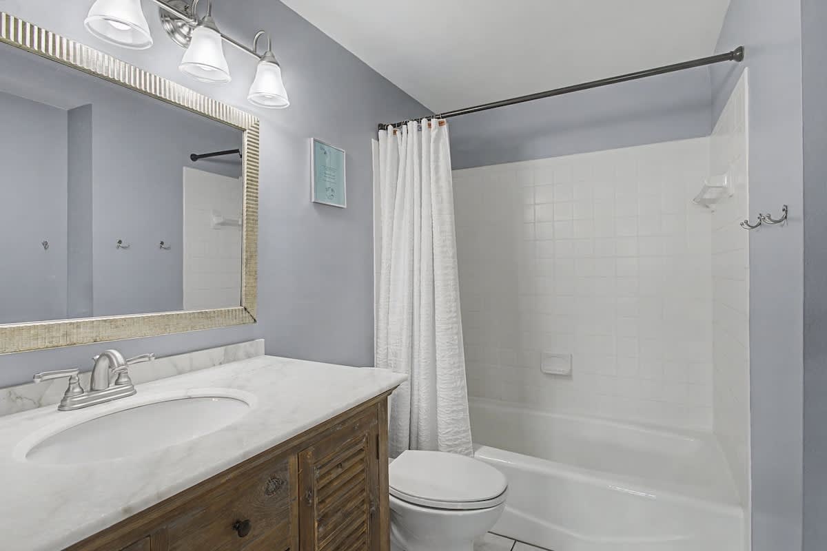 Your private bathroom features marble countertops, a spacious shower-tub combo, and coastal-inspired finishes for your relaxing getaway.