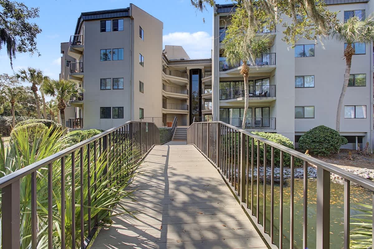 Modern beachside complex with lush tropical landscaping and charming bridge entrance creates a welcoming arrival experience.
