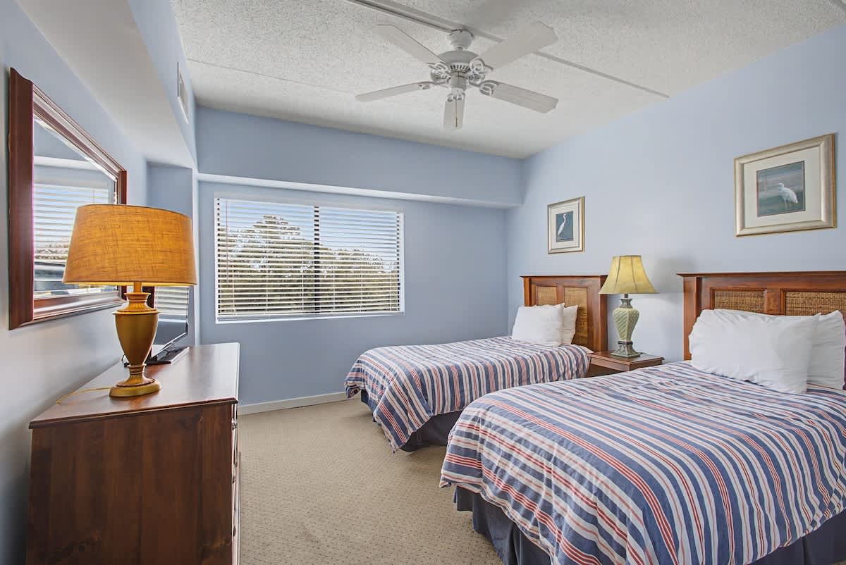 Drift off in comfort with twin beds, soft linens, and a gentle ceiling fan creating the perfect sleep sanctuary.