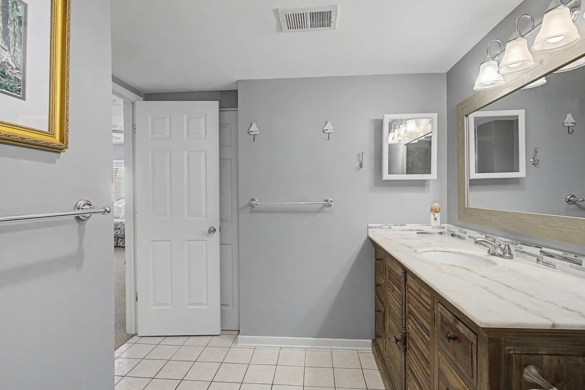 Step into your elegant bathroom featuring marble countertops, warm wood vanity, and thoughtful accessibility touches for your comfort.