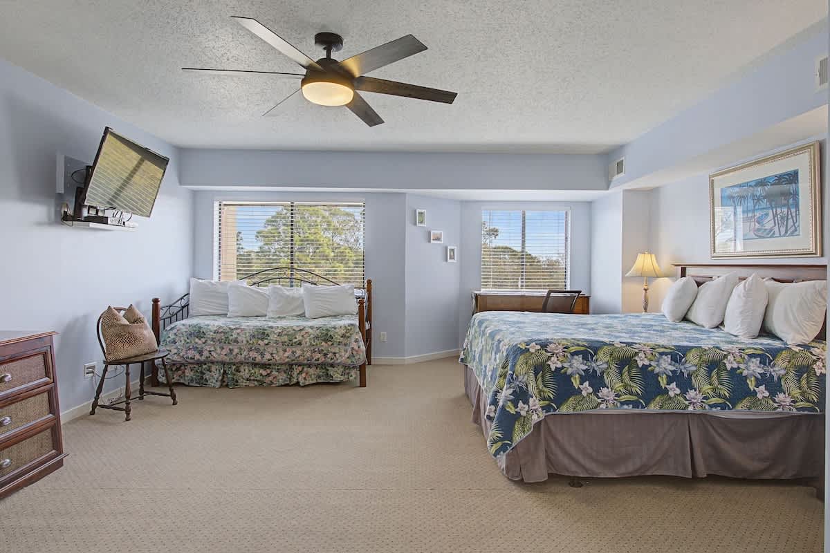 Sleep peacefully in your spacious room with tropical-themed bedding, modern ceiling fan, and views of lush greenery through your private windows.