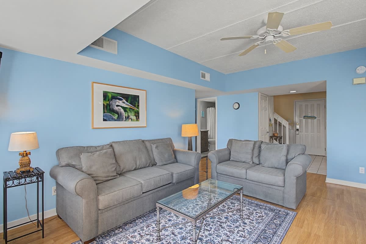 Unwind in your bright living space with plush gray sofas and cheerful blue walls that create a coastal feel.