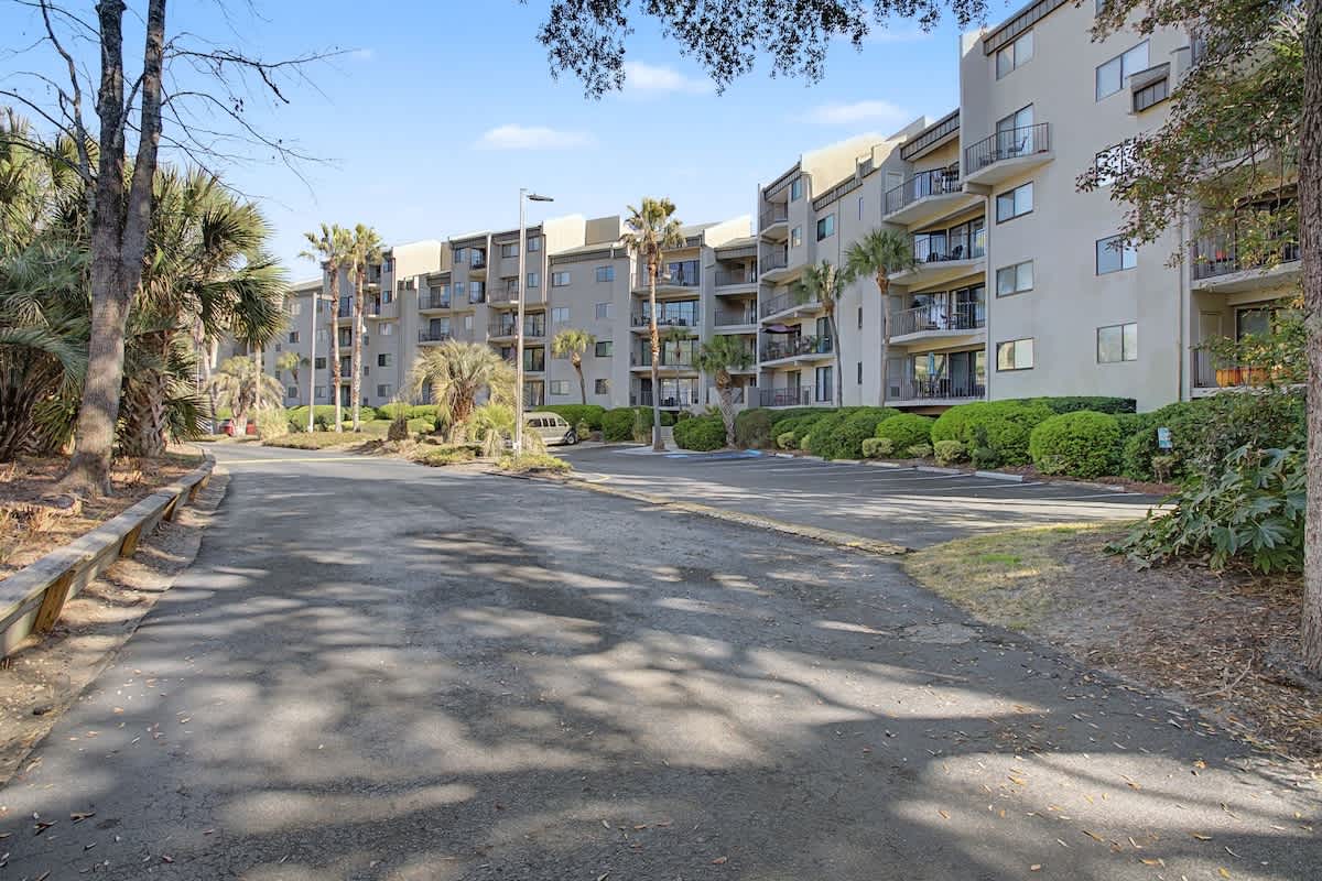 Modern multi-story vacation rental complex surrounded by lush tropical landscaping and mature palm trees with convenient on-site parking.
