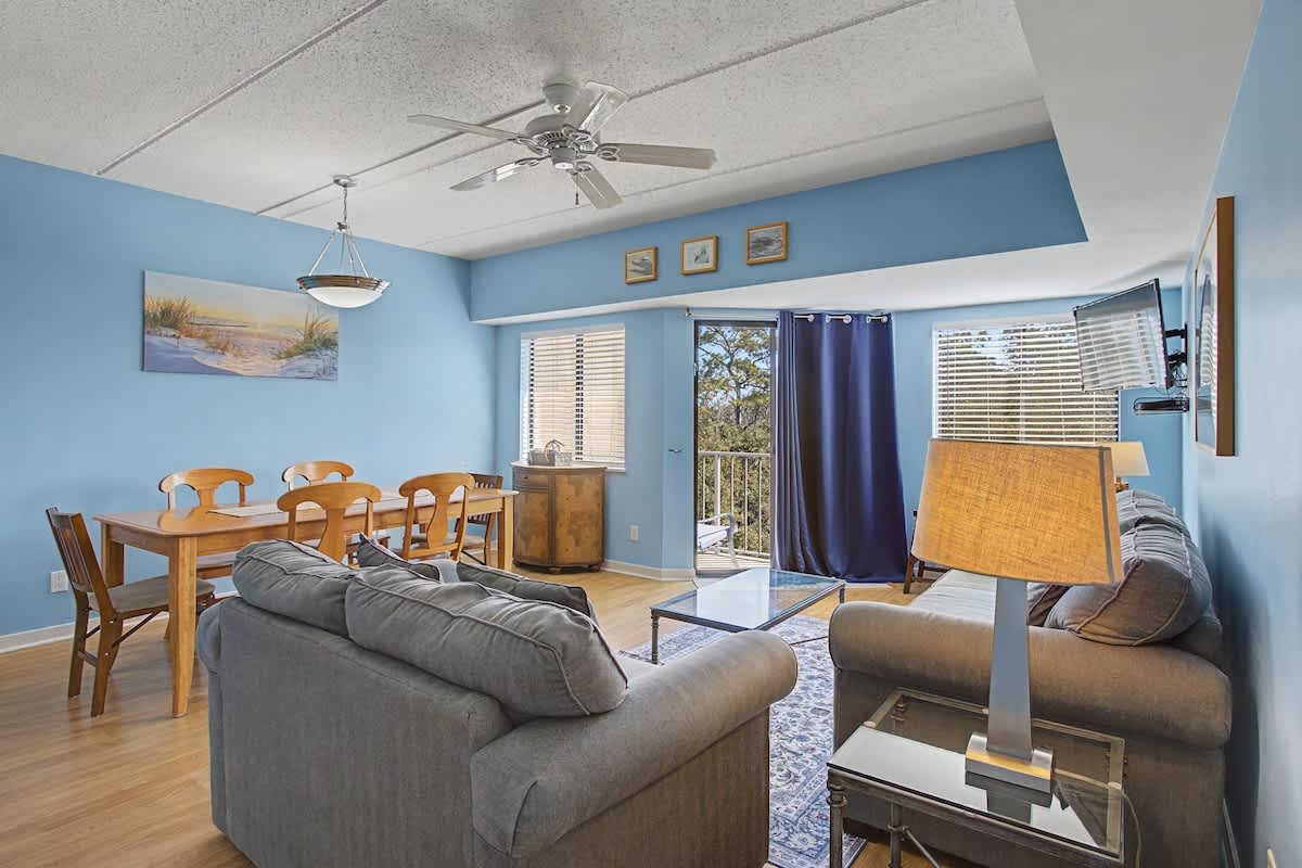 Relax in your bright, coastal-themed living space where soft blue walls and comfortable seating create the perfect atmosphere for unwinding after your adventures.