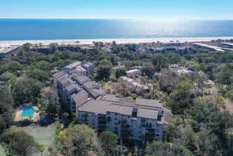 Beachfront resort complex nestled among coastal trees with direct beach access and nearby amenities.