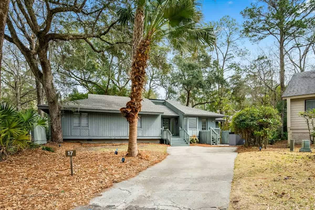 Charming coastal retreat nestled among mature trees and tropical palms, offering a peaceful escape with convenient parking and welcoming entrance.