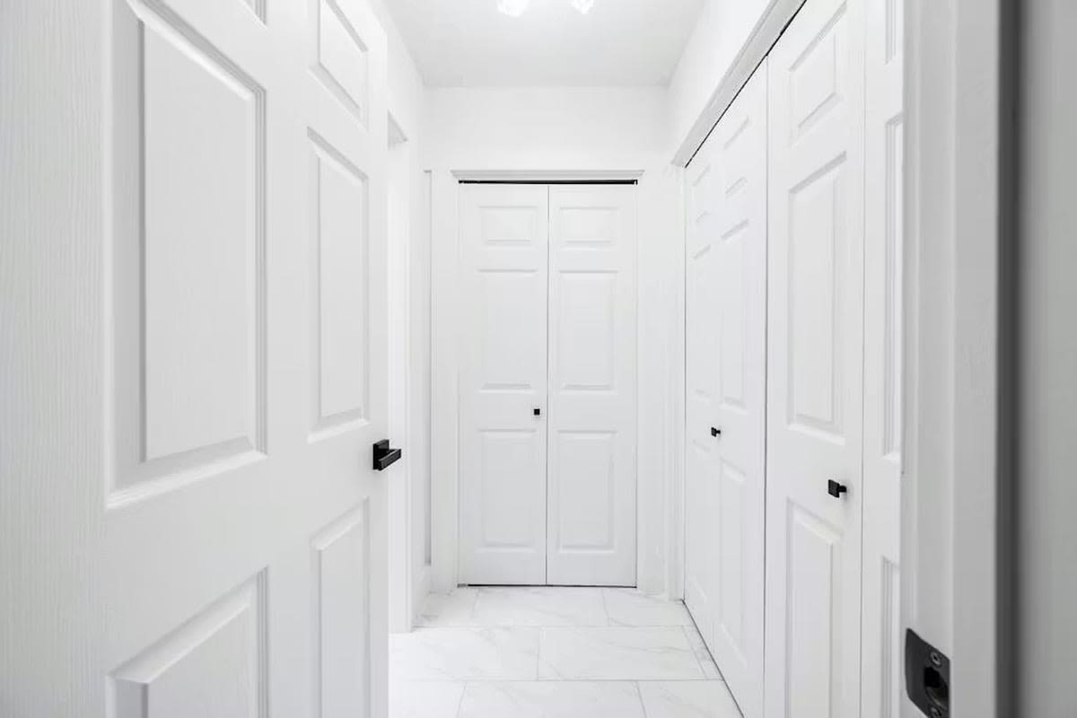 Step into your pristine hallway featuring elegant white doors and clean lines that create a sophisticated, welcoming atmosphere throughout your stay.