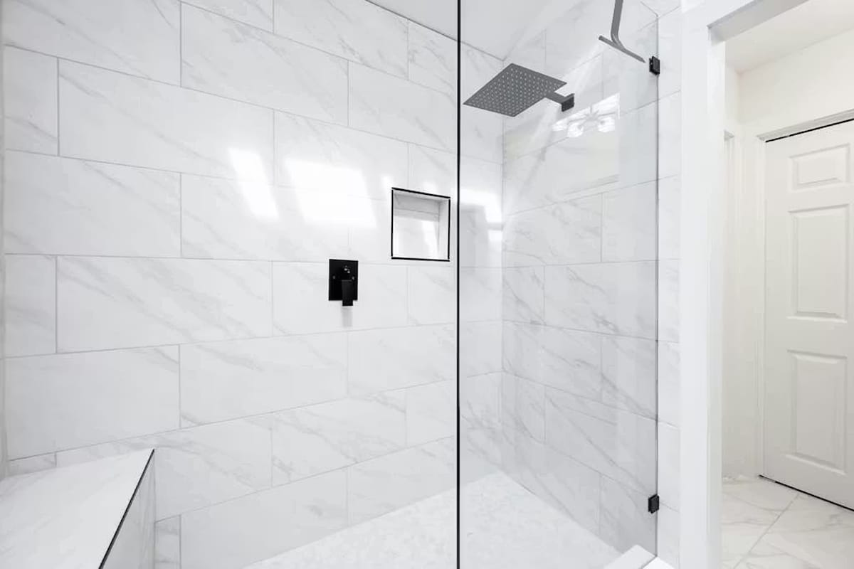 Step into your spa-like shower with luxurious marble tiles and a sleek rainfall showerhead for your ultimate relaxation.