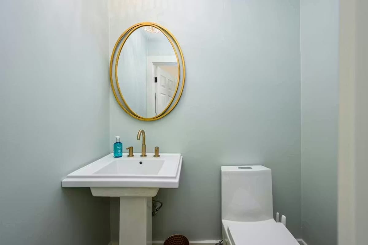 Step into your beautifully appointed powder room with elegant gold-framed mirror and modern fixtures for your comfort.