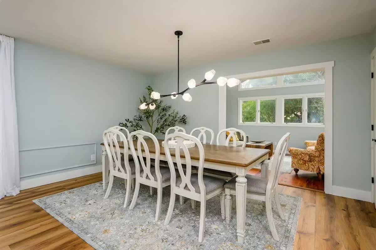 You'll love gathering around this elegant dining table, where natural light streams through large windows and modern pendant lighting creates the perfect ambiance for memorable meals.