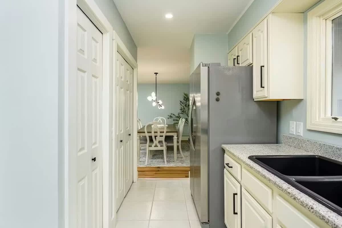 Your sleek galley kitchen features granite counters, white cabinets, and a gleaming stainless steel refrigerator, perfectly equipped for your culinary adventures.