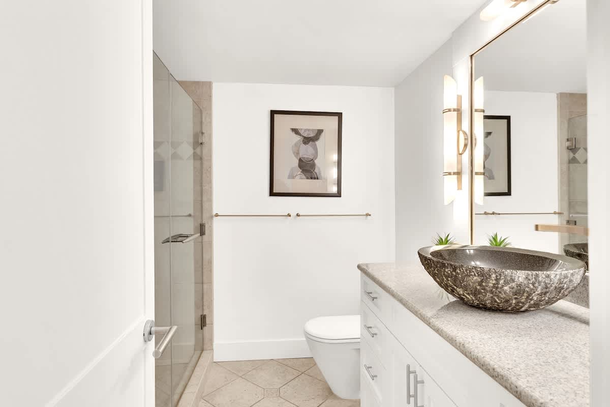 Unwind in your elegant bathroom featuring a stunning stone vessel sink and spacious walk-in shower with modern fixtures.