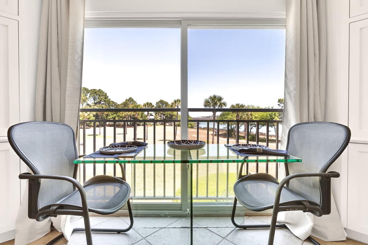 Enjoy intimate meals at your private glass dining table with stunning golf course views through floor-to-ceiling windows.
