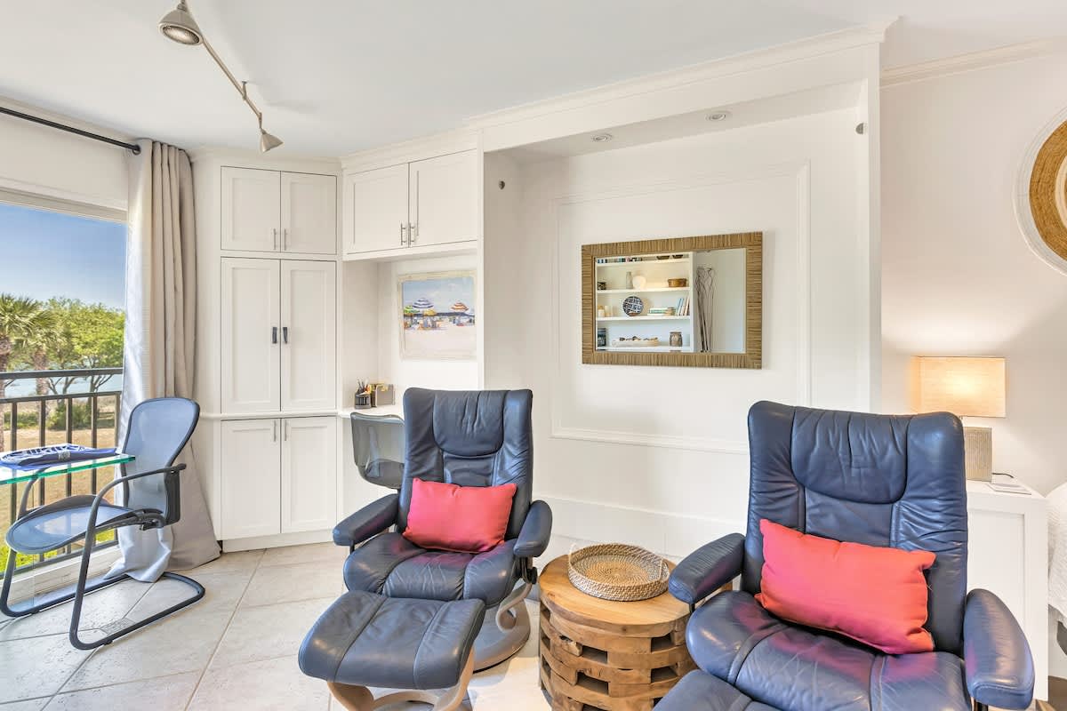 Sink into plush leather recliners with vibrant accent pillows while enjoying natural light streaming through your private balcony doors.