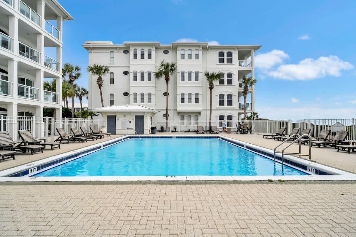Beautiful community pool complete with sun loungers overlooks the emerald waters of the Gulf.