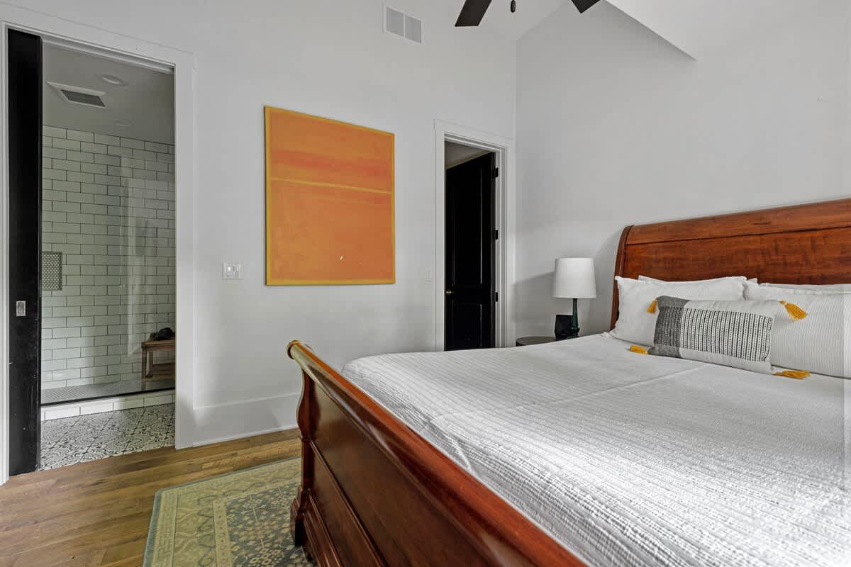 Warm wood, soft linens, and a sleek tiled bath just beyond.
