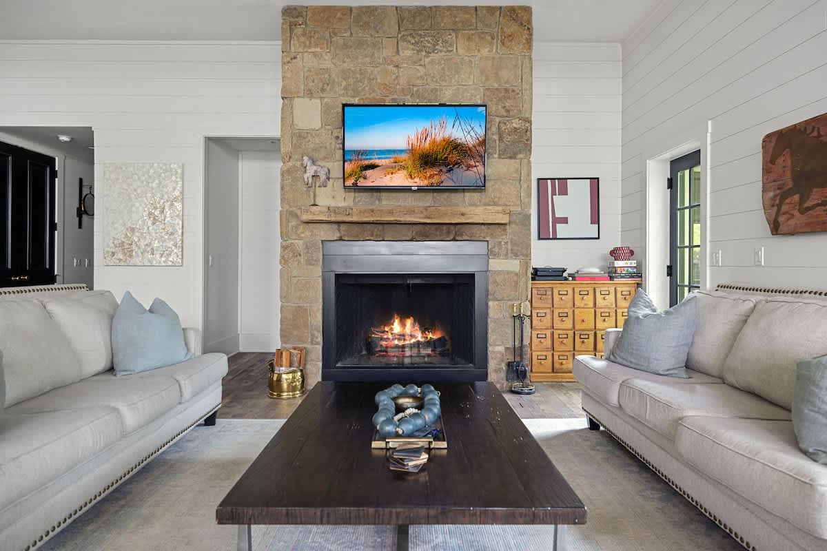 A classic stone fireplace is the centerpiece of the beautifully lit living room.
