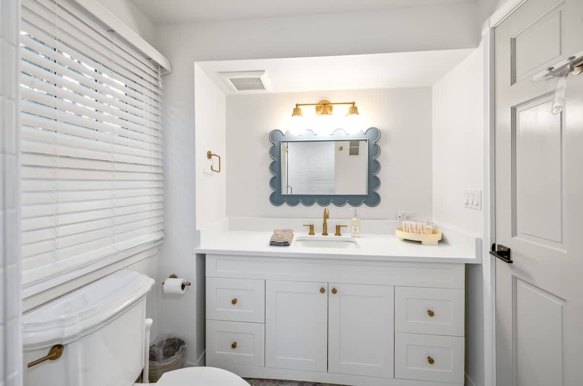 Simple elegance in this bathroom with white cabinets and a window overlooking nature.