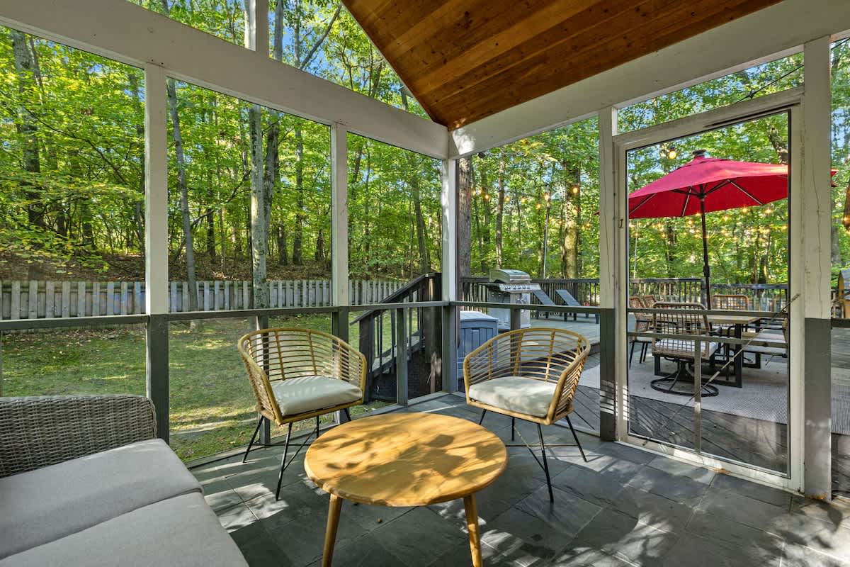 Just outside the screened-in porch is a relaxing deck, patio set + fenced yard.