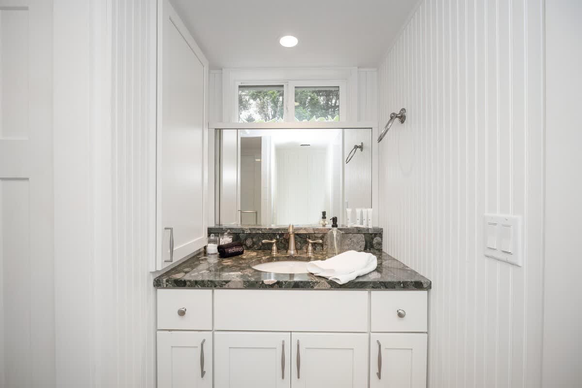 The lower-level bathroom has a tiled walk-in shower and custom vanity sink.
