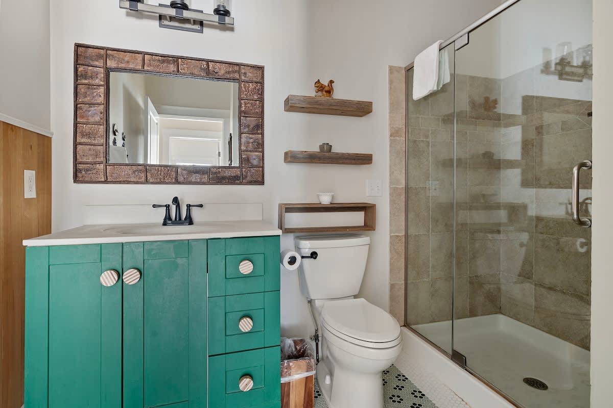 This bathroom features a tiled walk-in shower, stone-top vanity, eclectic decor.