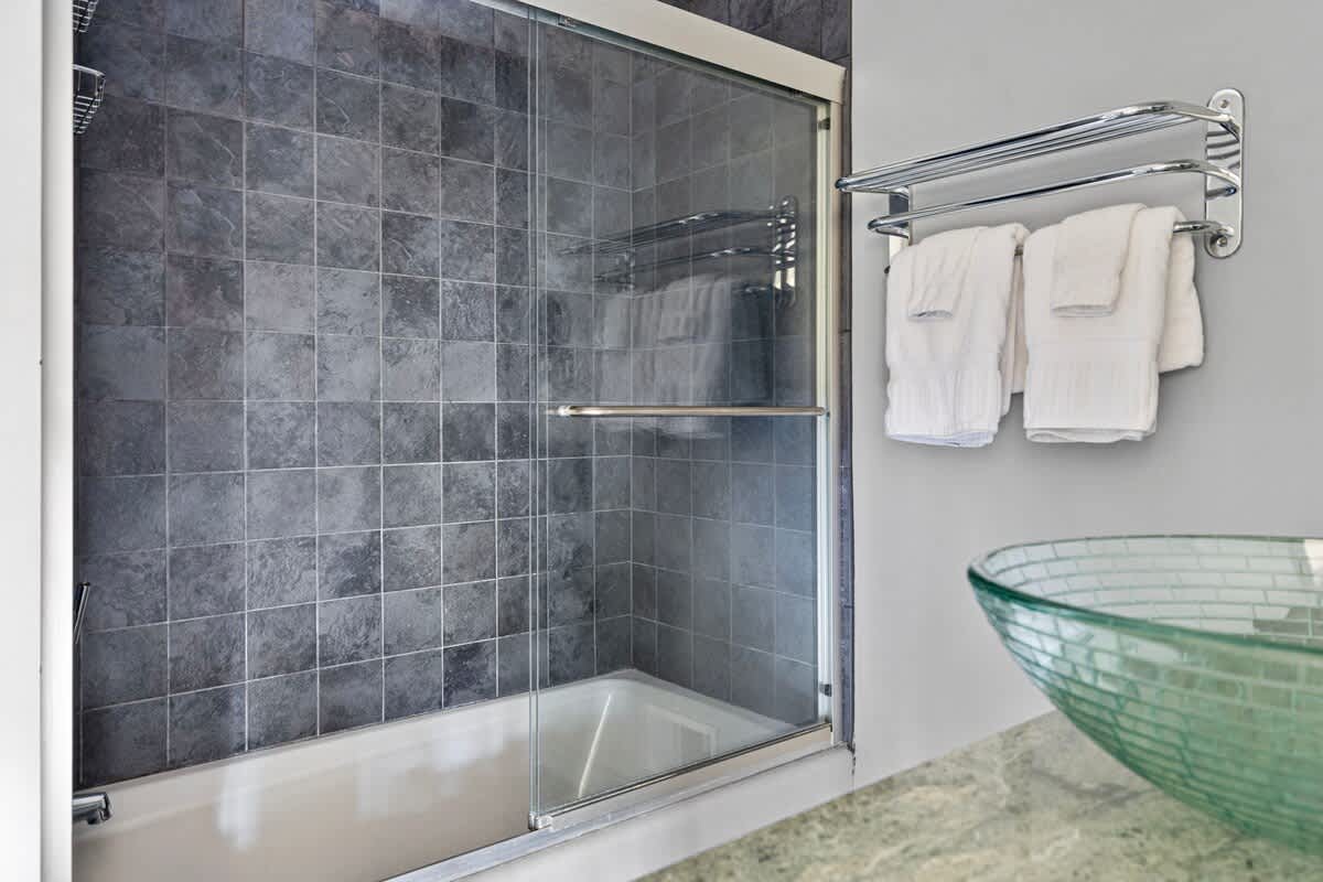 This sumptuous bathroom has a tiled shower-tub and glass-bowl vanity sink.