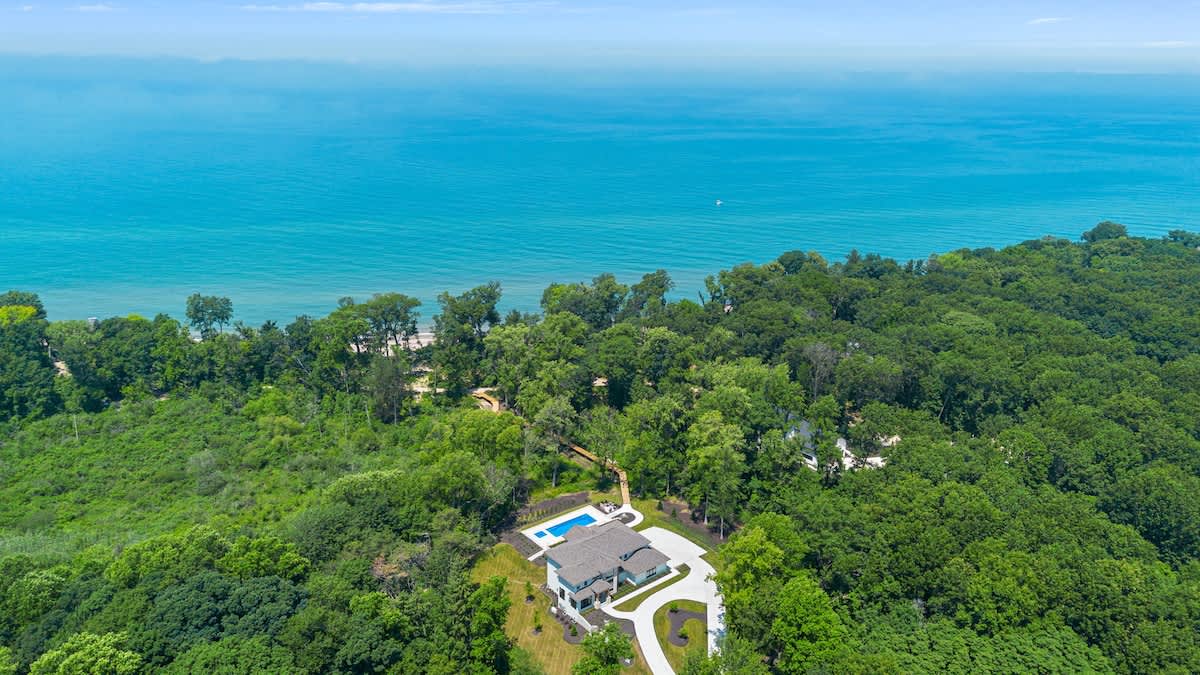 This aerial view captures the beauty of a house nestled amidst lush trees and serene waters.