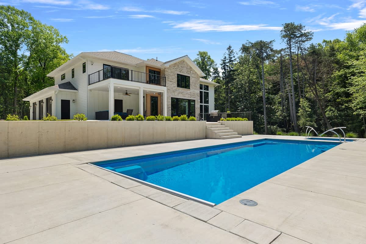 Blue skies, green trees, and a sparkling swimming pool.