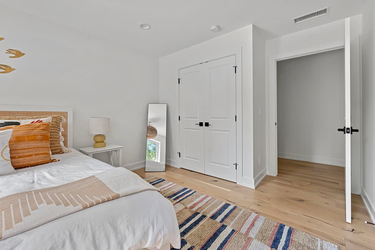 Indulge in comfort and style in this stunning bedroom with a luxurious white bed and beautiful wooden flooring for moments of pure relaxation.