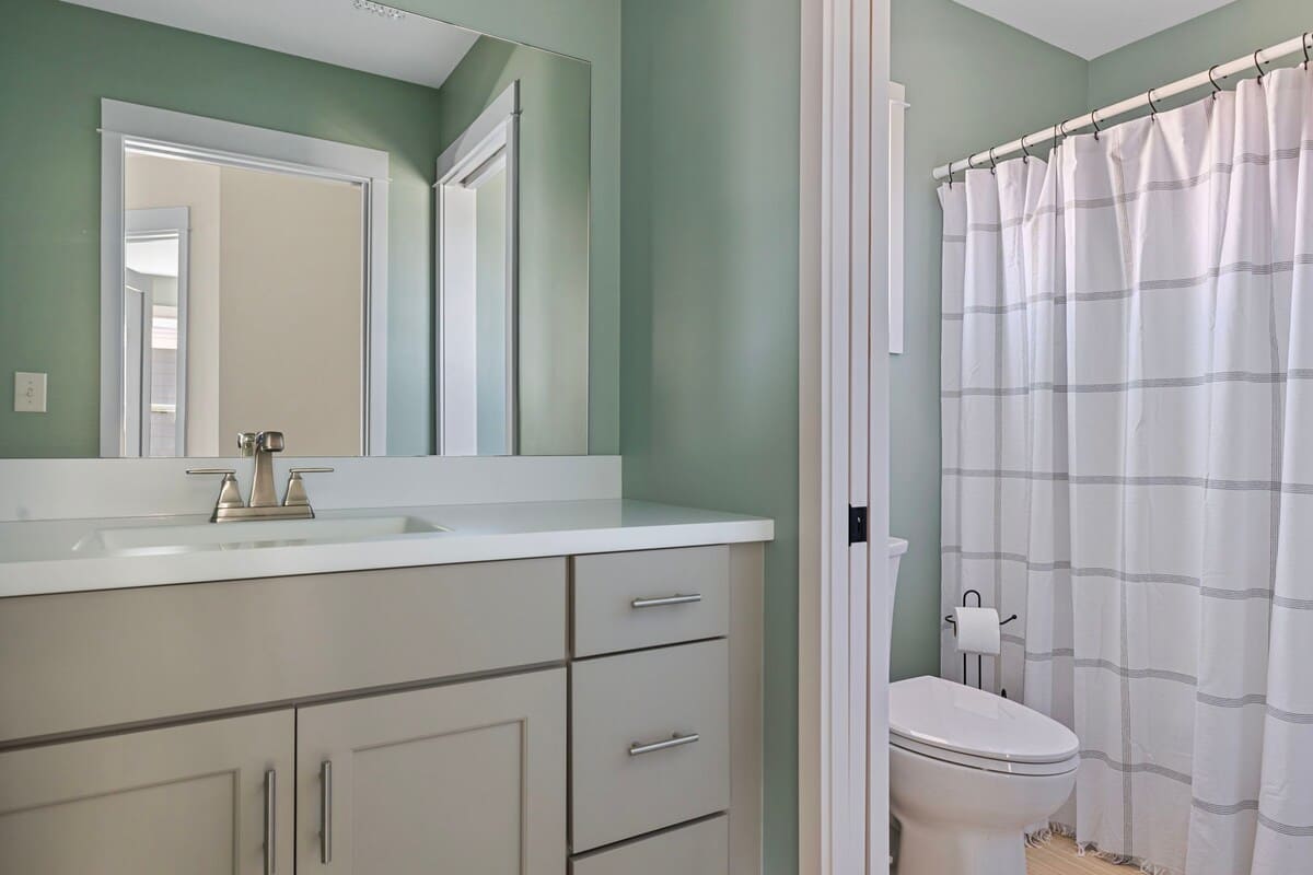 This sleek full bathroom has a shower-soaker tub combo and stone-top vanity.